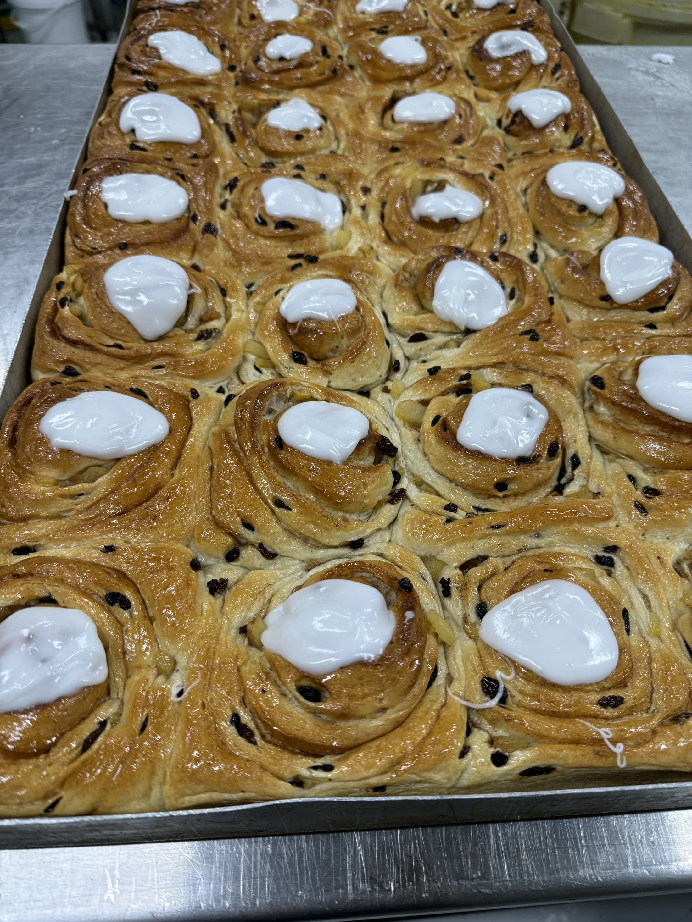 Tray of freshly baked apple scrolls topped with white icing at Kipling's Bakery, Port Wakefield